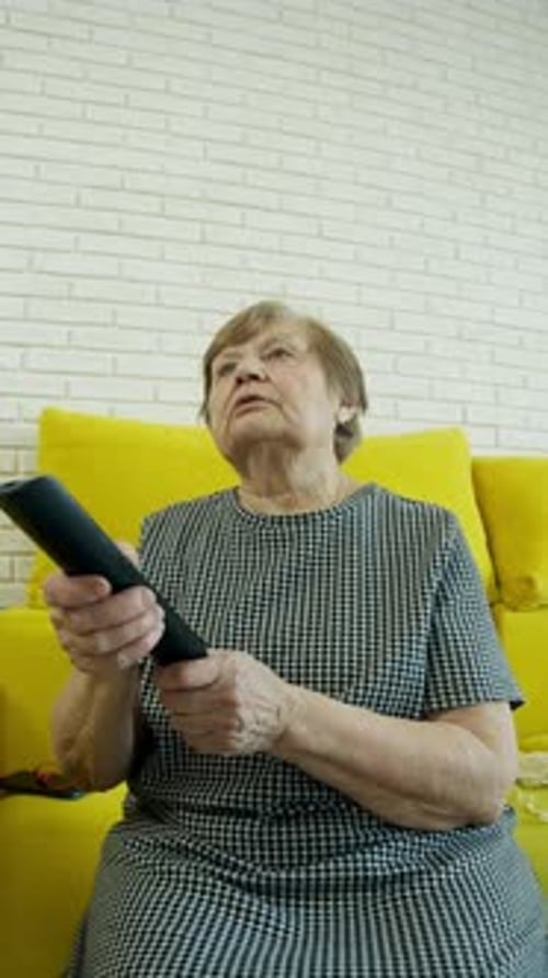 Senior Woman Using Remote Control Watching Television