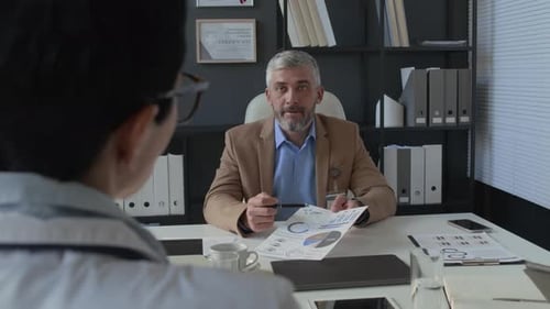 Medical Professional Discussing Charts During Meeting