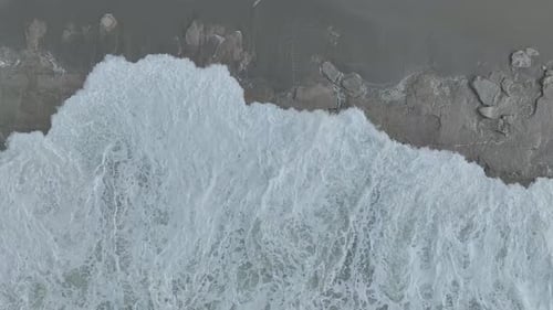 Aerial Video Intense Stormy Sea Spreads Beautiful Foam Textures on the Scenic Shoreline