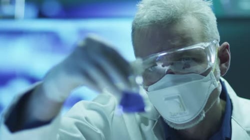 Scientist in Safety Glasses is Inspecting Chemical Reagents in Flask. Close-up.