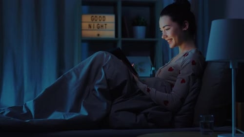 Young Woman Using Tablet in Bed at Night