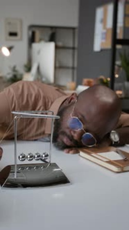 Bored Office Worker Watching Newton Cradle
