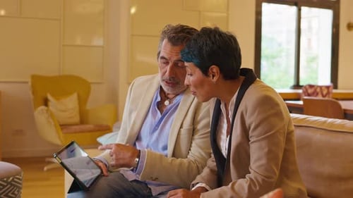 Adults Interact with Tablet Device Indoors on Couch