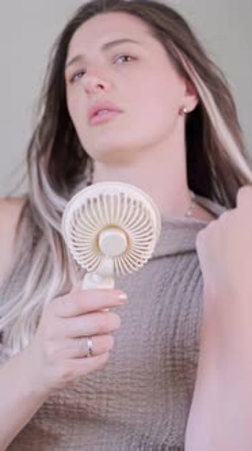 Woman Cooling Herself with a Portable Electric Fan