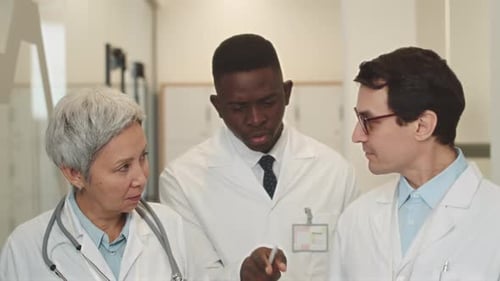 Doctors Talking while Walking along Corridor at Hospital