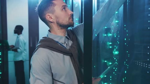 Man Inspecting Servers in Server Room With Tablet