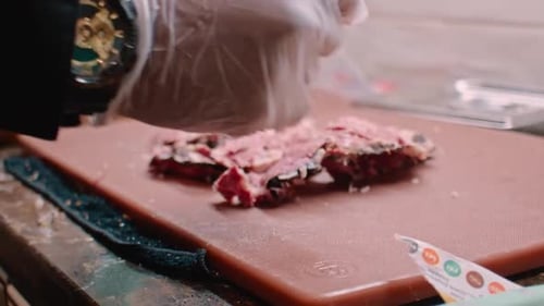 Hands in white gloves preparing pastrami meat for sandwich, close up