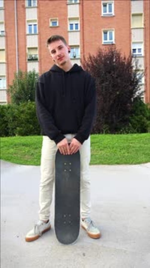 vertical Skater Posing Confidently with Skateboard in Skate park as Camera Approaches