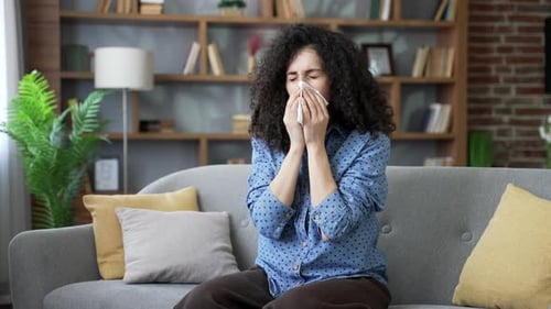 Woman Sitting on Couch Using Tissue Due to Illness