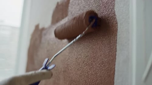 Close Up of Hand Painting Interior Wall Brown