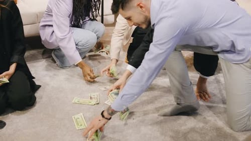 A Successful Multiethnic Group of Business Professionals Gathers Scattered Money From the Floor with