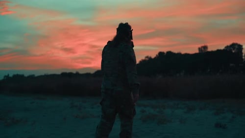 Silhouette of an American Soldier Wearing a Gas Mask Walking on the Beach Sunset