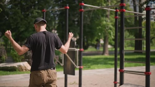 Man Warms Up Outdoors Individual Stretching And Exercising On Park Bars Man In Casual Sports