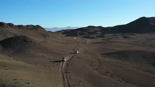 Cinematic rotating drone shot of a car caravan navigating through the Charyn Canyon, Kazakhstan