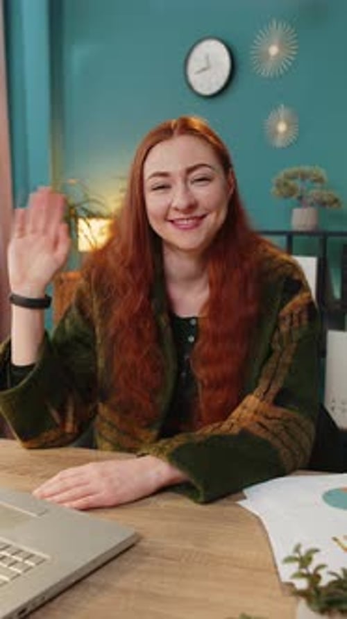 Smiling Woman Waving at Desk in Home