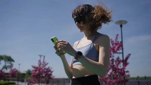 Sporty Woman Checking Smartwatch and Phone in Park