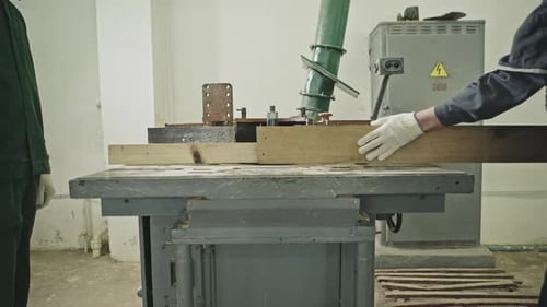 Two Workers Sawing Wooden Plank on Table Saw at Woodworking Workshop