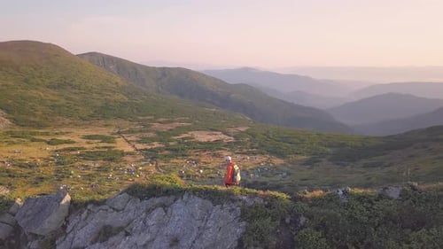 Tourist Hiker with a Backpack in Orange Jacket Walking on Mountain Path in Carpathian Mountains