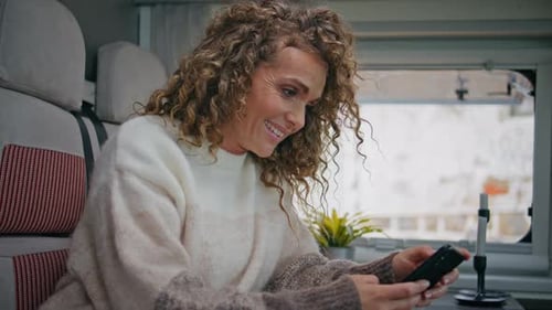 Cheerful Lady Watching Social Media at Cellphone in Camper Van Close Up
