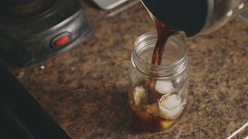 Pouring Iced Coffee into a Glass Jar