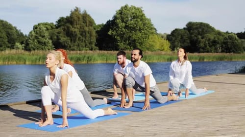 Fitness, Sport, With Healthy Lifestyle - Group of People Making Yoga Exercises on River or Lake...