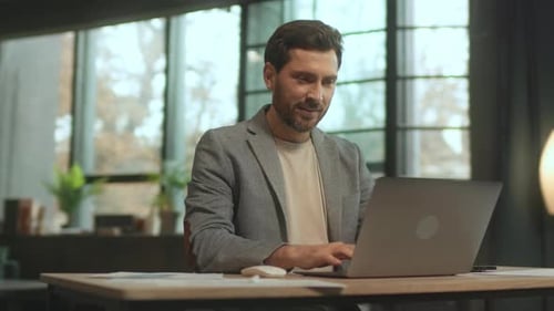 Man Celebrates Success While Working on Laptop