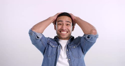A handsome young man celebrating against a pink background in the studio