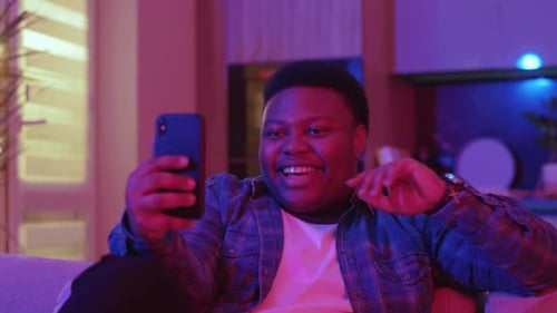Smiling man video chatting on phone in living room