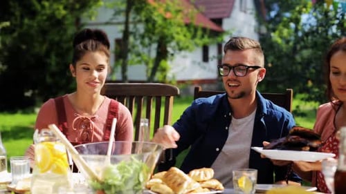 Happy young friends enjoying a summer garden party barbecue meal together