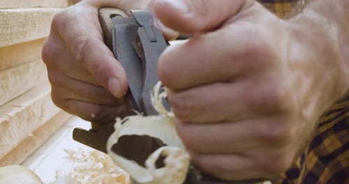 Man planing wood with hand plane outside