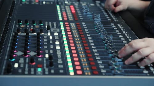 Hands Adjusting Audio Mixing Board Controls