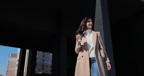 Young Business Woman Walks Around Modern Urban Area with Take Away Coffee