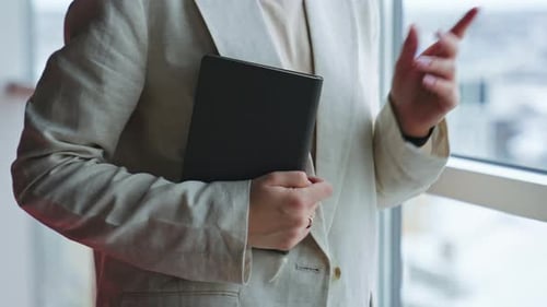 Businesswoman Stands Near Window Looking At Notebook