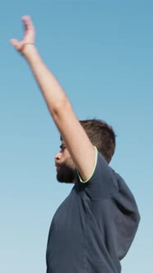 Young Adult Stretching Arms Up to Blue Sky