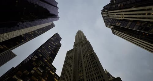 Vista hacia el cielo de imponentes rascacielos bajo un crepúsculo nublado