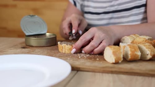 08 1La baguette en rodajas se unta con paté de una lata. Una mujer prepara sándwiches sencillos en un bosque