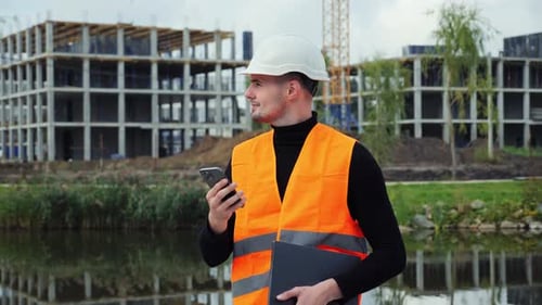 Young Engineer on Construction Site Using Cell Phone