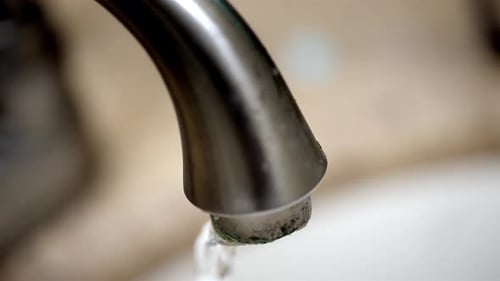 Close-Up of Water Pouring out of a Tap into the Bathroom Sink
