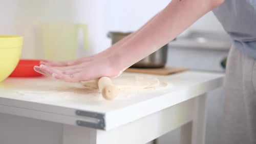 Flattening Dough with a Rolling Pin on Table