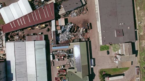 Flying over, looking down at industrial buildings, factories and scrapyard.