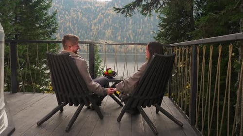 Couple Holding Hands Relaxing on Deck Overlooking Lake