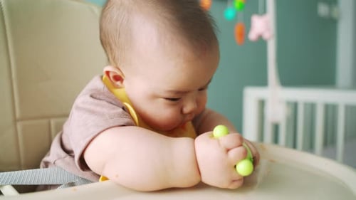 Cute Infant Eating Food in Highchair at Home