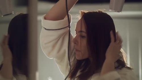 Woman Dries Hair in Mirror Wearing a Robe