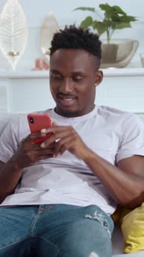 Man Relaxing on Couch Using Mobile Phone