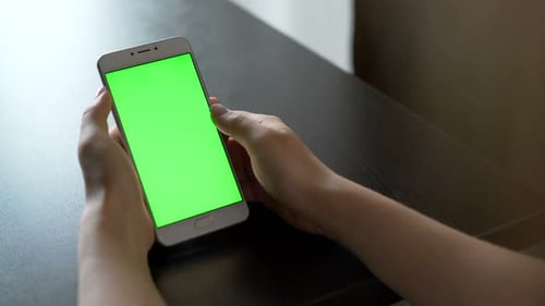 Woman using smartphone with green screen for social media browsing closeup