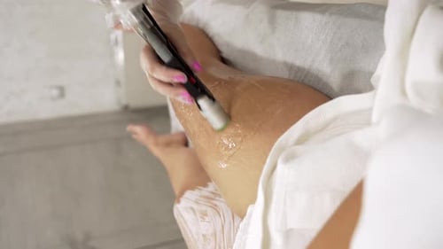 Vertical Close Up Video of Professional Cosmetologist Doing Laser Hair Removal of Legs to Young