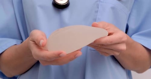 Doctor Holding Breast Implant in Hospital Setting