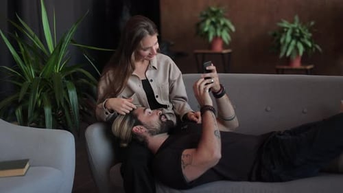 Couple Relaxing on Sofa Looking at Phone