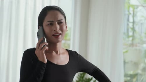 Woman Talking Angrily on Phone while Holding Box