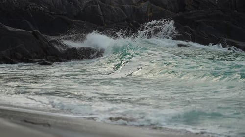Starke Wellen krachen an der felsigen Küste. Wasserspray steigt in der Luft auf. Zeitlupe, Nahaufnahme